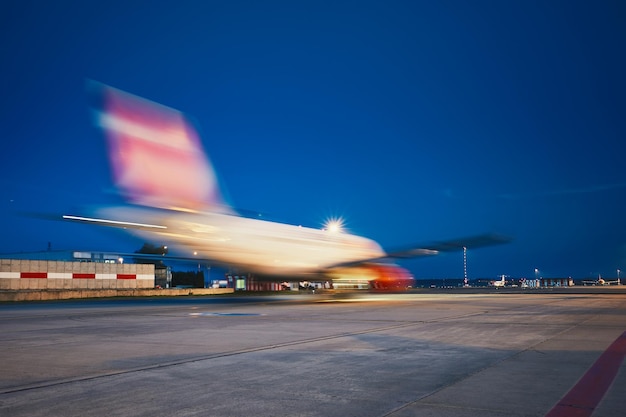 Avión desenfocado en la pista contra un cielo azul claro por la noche