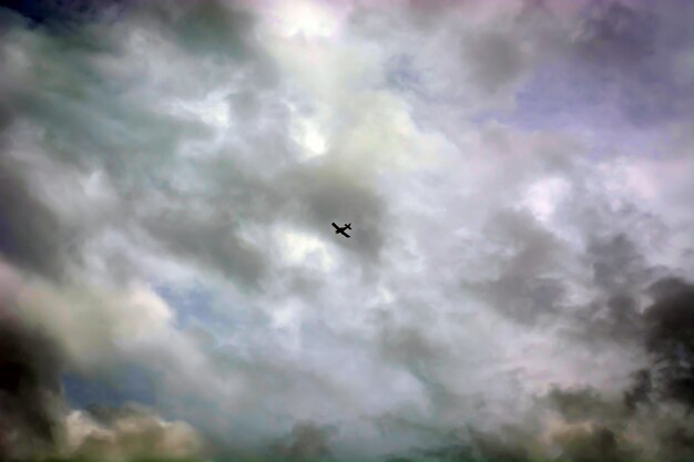 Avión con estela muy alta en el cielo entre nubes.