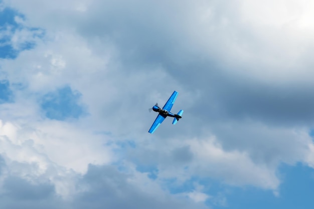 Avión de hélice deportivo azul volando en el cielo azul con nubes