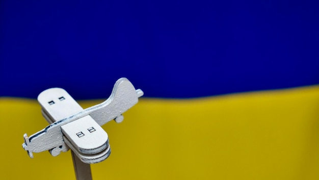 Avión de juguete de madera decorativo sobre el fondo azul amarillo de la bandera ucraniana Rusia atacó a Ucrania