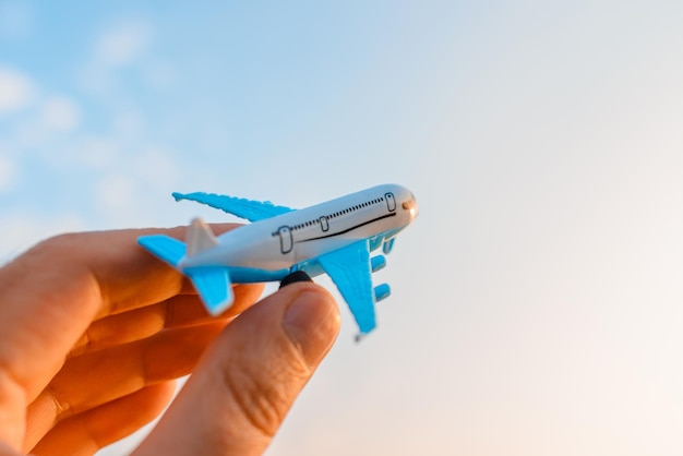 Avión de juguete en la mano de un hombre sobre un fondo de cielo con nubesHombre sosteniendo el avión en la mano y volando sobre el fondo nublado del cielo azul del atardecerConcepto de motivación para viajar