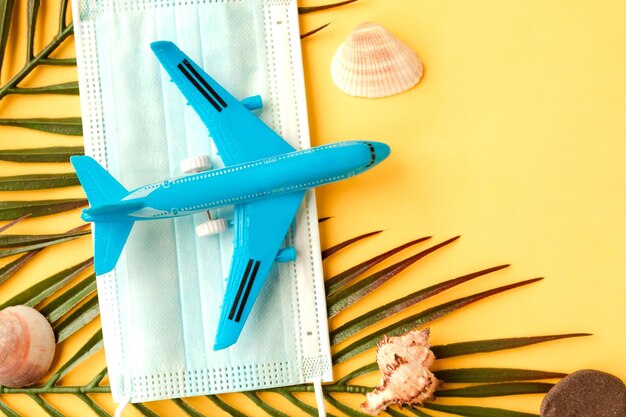 Foto avión de juguete y máscara médica facial en fondo amarillo viaje durante el concepto de pandemia de coronavirus