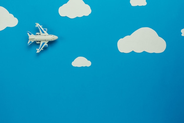 Foto avión de juguete y nubes artificiales contra un fondo azul