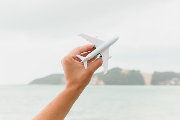 Avión de juguete volando, mostrando la playa y el cielo, representando viajes y turismo