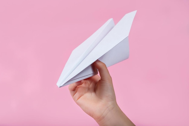 Avión de mano y papel sobre fondo rosa juegos de niños