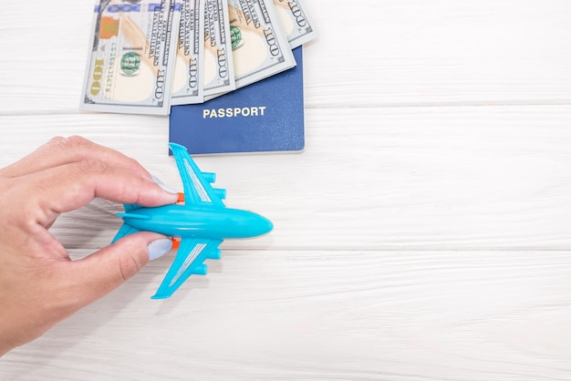 avión en mano, pasaportes con dólares en una superficie de madera con espacio de copia.