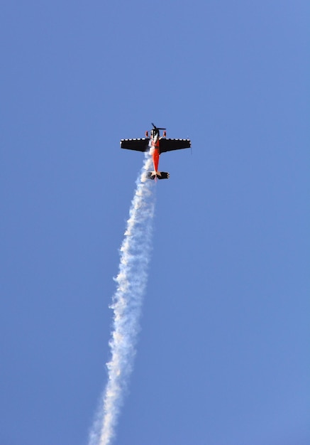 Avión militar vuela con humo en el cielo azul