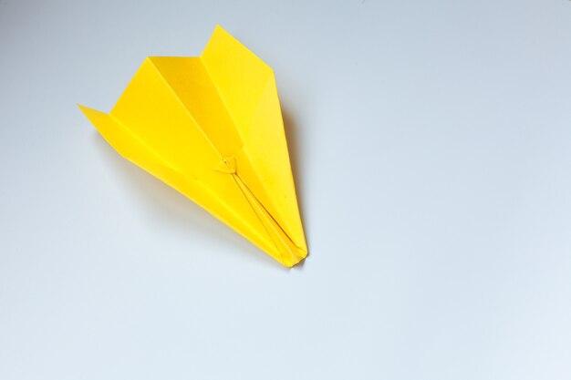 Avión de origami amarillo sobre un fondo blanco.