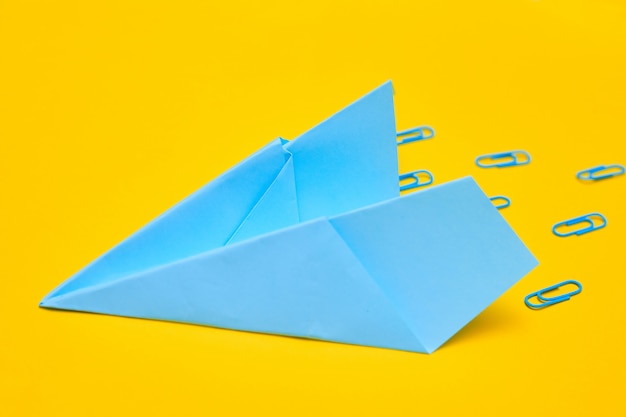 Foto avión de papel azul sobre un fondo amarillo