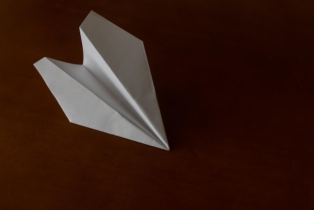 Avión de papel blanco sobre fondo marrón, concepto de viajes y vacaciones.