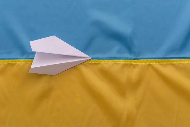 Avión de papel en el fondo de la bandera de Ucrania