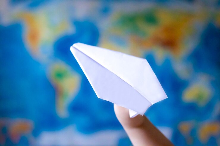 Foto avión de papel en la mano sobre el fondo del colorido mapa geográfico mundial. viajes, planificación de vacaciones