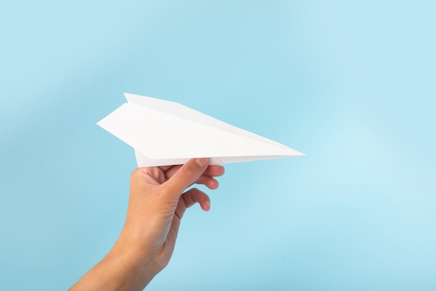 Avión de papel en mano sobre una plantilla de diseño de fondo azul