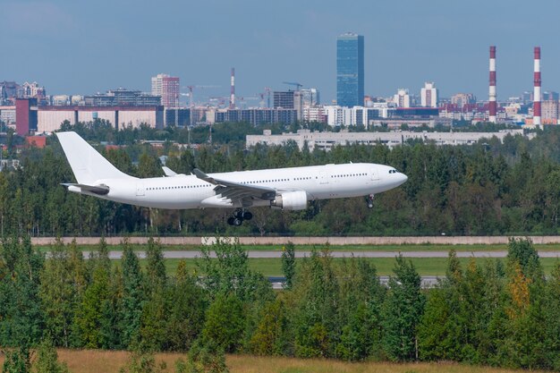 Avión de pasajeros blanco aterrizó en la pista del aeropuerto en el contexto de la ciudad.