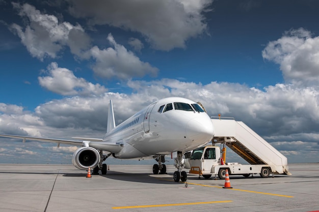 Avión de pasajeros blanco con escaleras de embarque en la plataforma del aeropuerto