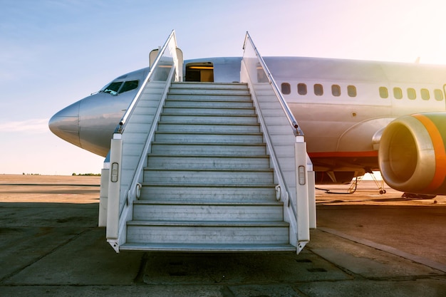 Avión de pasajeros con escalones de embarque en el sol de la mañana