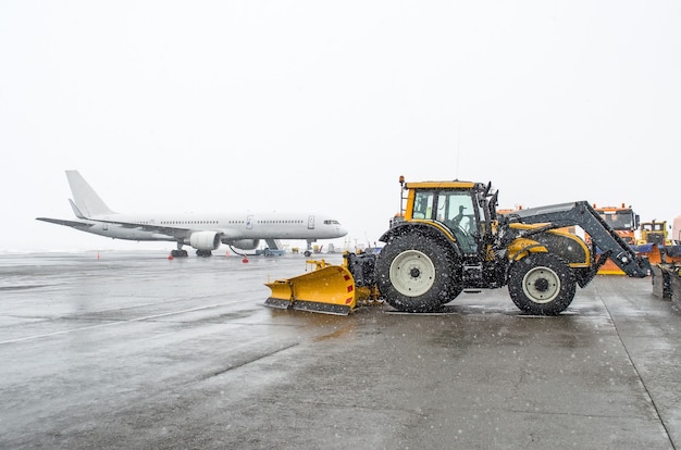 Avión de pasajeros en el estacionamiento y un tractor de nieve con nieve en invierno.