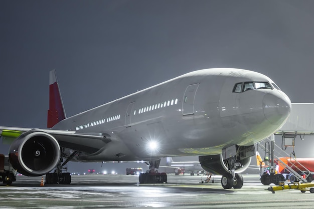 Avión de pasajeros de fuselaje ancho en la plataforma del aeropuerto en la noche de invierno