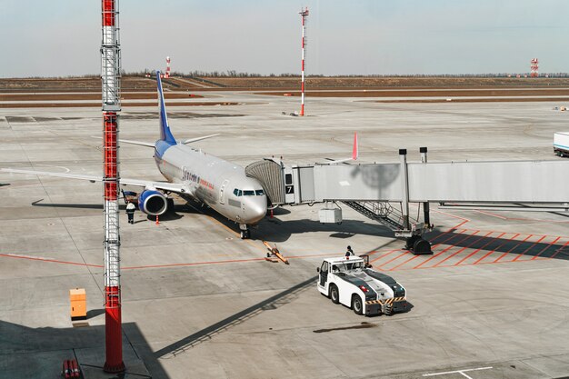 Avión de pasajeros gris atracado en el aeropuerto preparándose para el vuelo