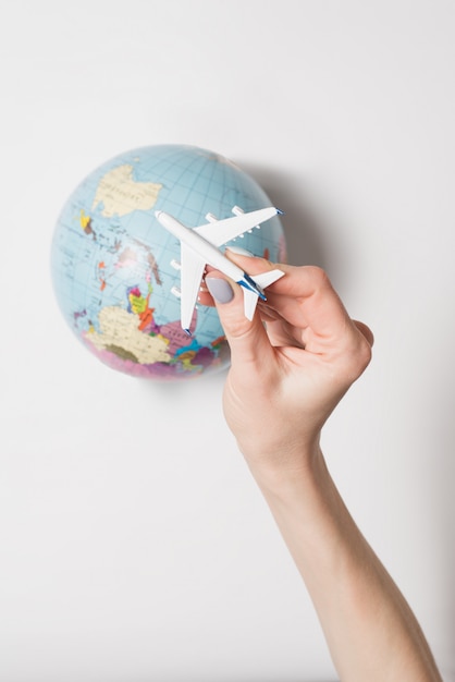 Foto avión de pasajeros en una mano femenina, globo terráqueo. concepto de vuelo