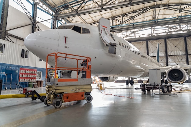 Avión de pasajeros en mantenimiento de reparación de motor y fuselaje en hangar