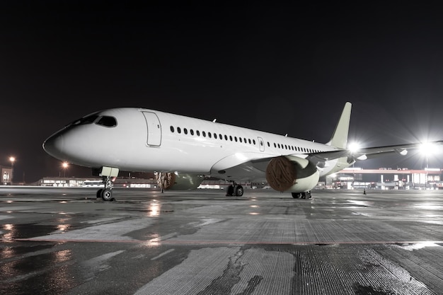 Avión de pasajeros moderno en la plataforma del aeropuerto de noche