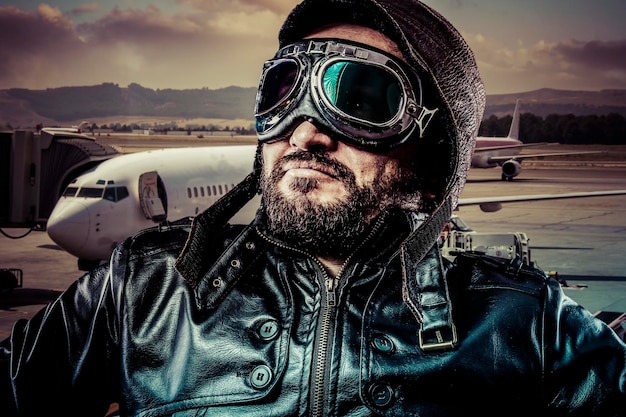 Foto avión, piloto pride con chaqueta de cuero negro y gafas viejas