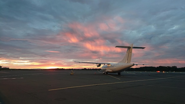 Foto avión en la pista del aeropuerto contra el cielo durante la puesta de sol