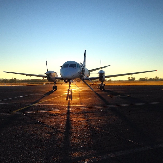 Foto avión en la pista de aterrizaje al atardecer