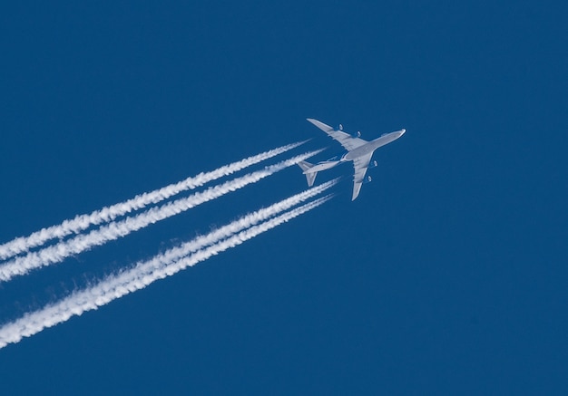 Avión a reacción con una pluma blanca sobre un cielo azul