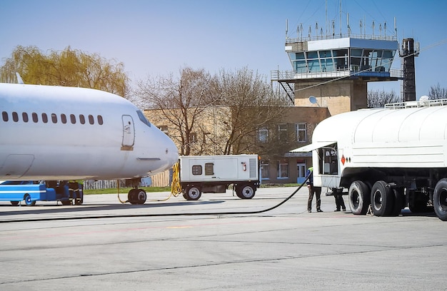 Avión repostando con un camión cisterna de alta presión Un avión de pasajeros está siendo repostado desde un camión de suministros Servicio aeroportuario