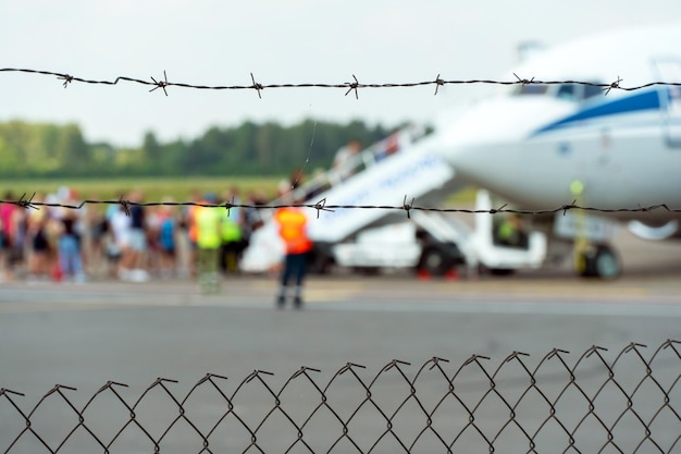 Un avión en el territorio del aeropuerto contra el fondo de alambre de púas Territorio cerrado de un aeródromo privado Aterrizaje de emergencia del avión El avión está en la pista