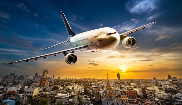 Avión de transporte sobrevolando la ciudad sobre fondo hermoso atardecer