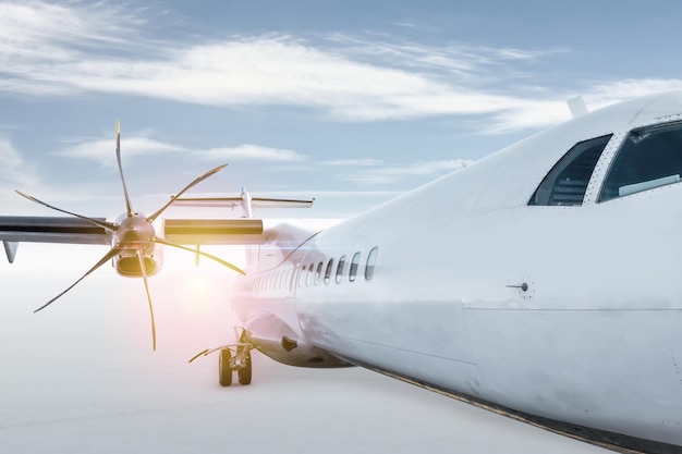 Avión turbohélice de pasajeros blanco aislado sobre fondo brillante con cielo