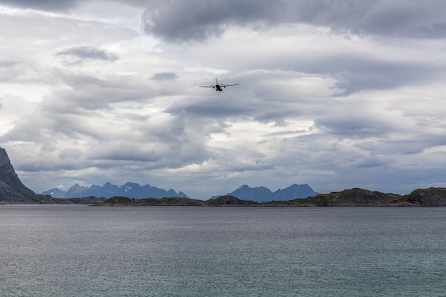 Avión volando en el cielo nublado de los fiordos noruegos, Lofoten