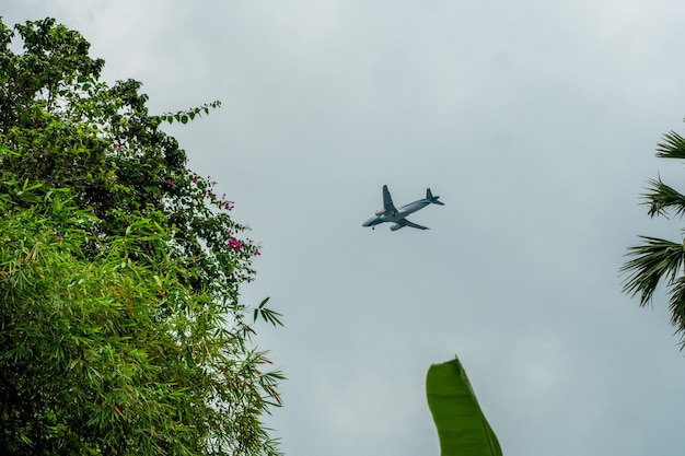 Avión volando en un cielo nublado y preparándose para aterrizar en una isla tropical