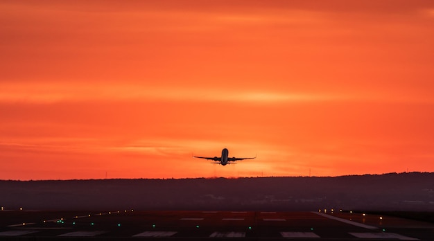 Foto avión volando contra el cielo naranja