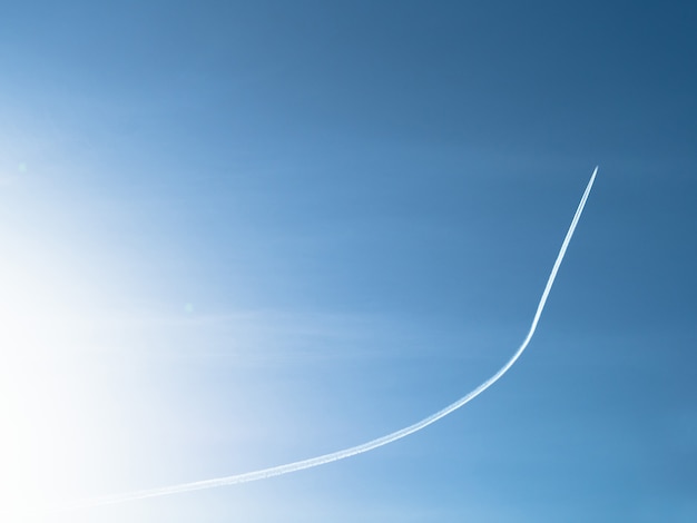 Avión volando y dejando rastro en el fondo del cielo azul