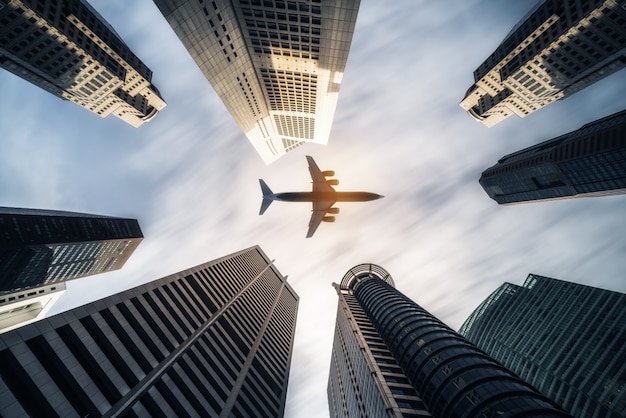 Avión volando sobre edificios comerciales de la ciudad, rascacielos de gran altura