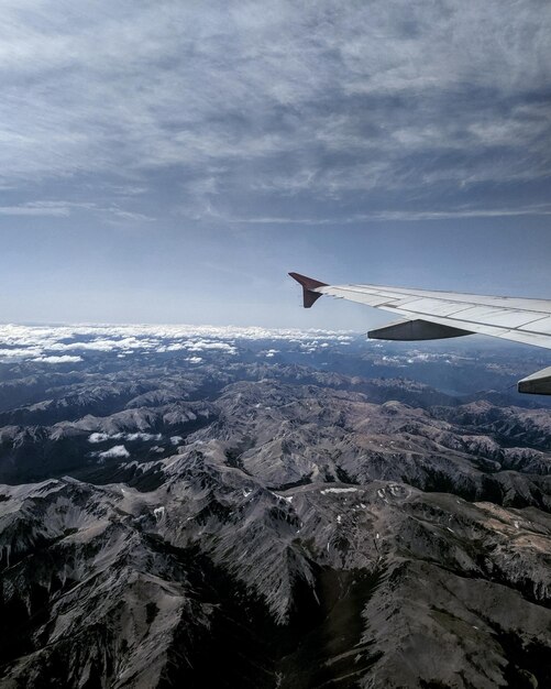 Foto avión volando sobre una montaña cubierta de nieve contra el cielo