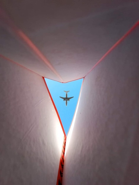 Un avión vuela a través de un túnel con un cielo azul de fondo.