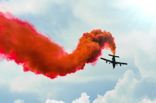 Avión vuela en zigzag con un rastro rojo humo en el cielo.