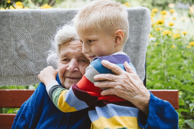 Avó abraçando neto enquanto está sentada em um banco ao ar livre