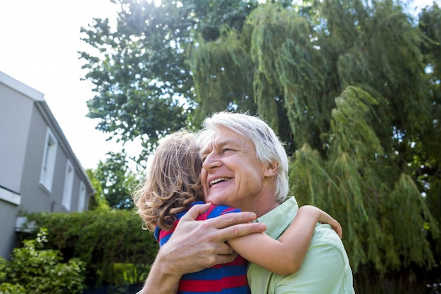 Avô, abraçando o neto no quintal