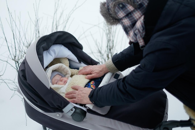 Avô andando com um carrinho de bebê em dia de inverno nevado