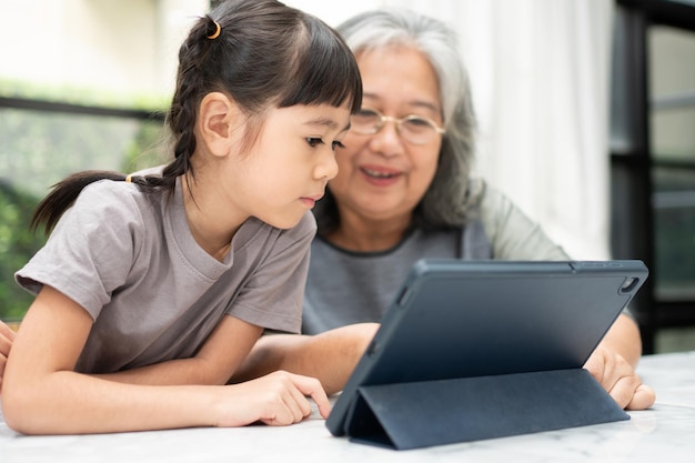 Avó asiática com seus dois netos se divertindo e jogando jogos de educação online