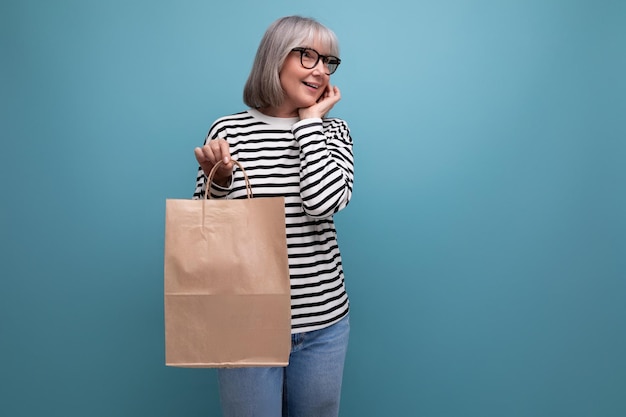 Avó bem cuidada com compras em uma bolsa de artesanato em um fundo brilhante com