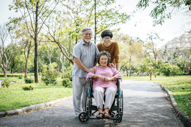 Avô com deficiência alegre em cadeira de rodas, congratulando-se com sua família feliz