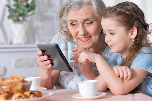 Avó com neta jogando em um computador tablet