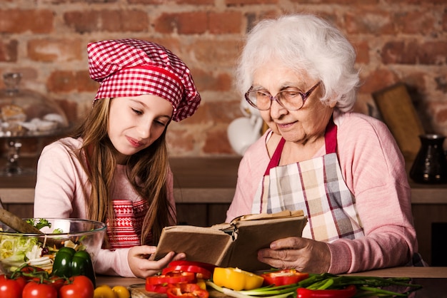 Avó com neta usando livro de culinária